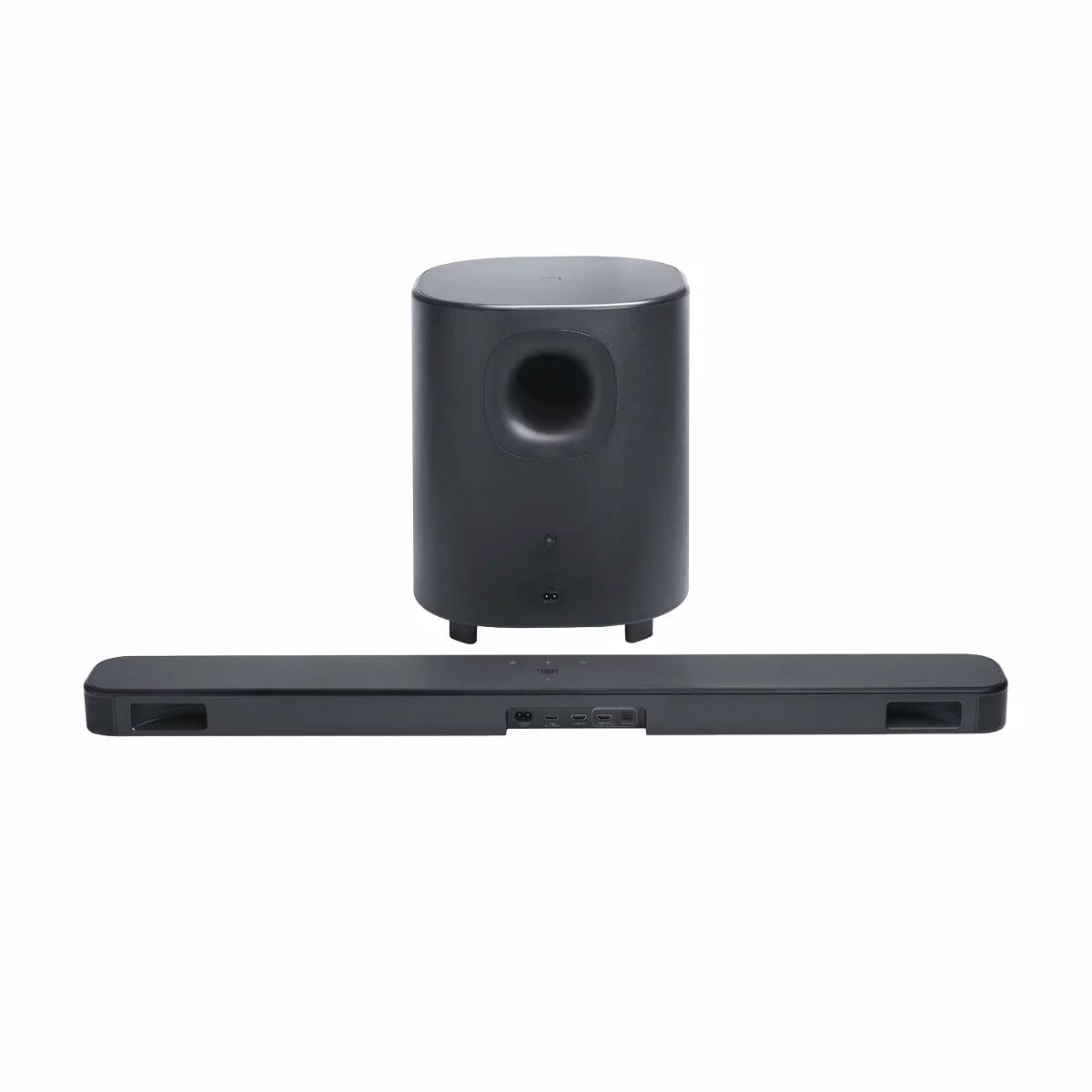 JBL BAR 500MK2 black 5.1 channel soundbar mounted under a wall-mounted TV with its 10-inch wireless subwoofer positioned on a hard-wood floor.