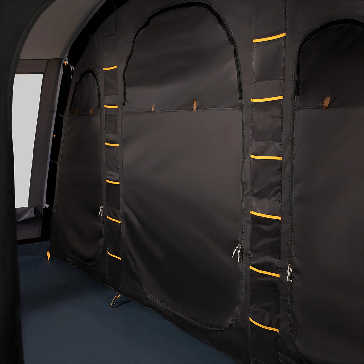 A green and grey Kampa Dawlish 4 Person Tunnel Tent pitched on a lush green grass campsite with its large side door open revealing the darkened inner sleeping compartment.