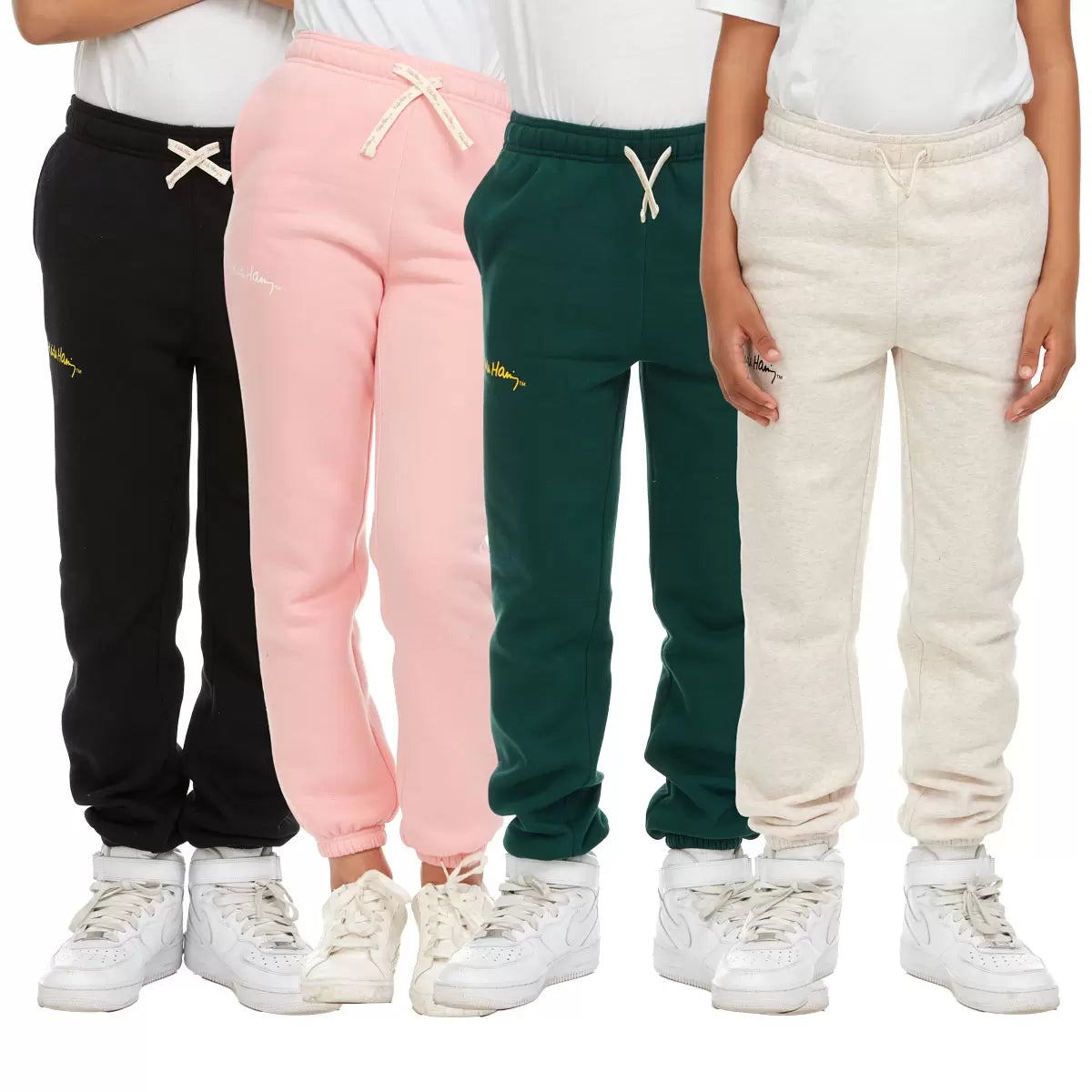Front view of Keith Haring youth fleece joggers in green showing iconic pop art graphics, side pockets, and an elastic drawstring waistband.