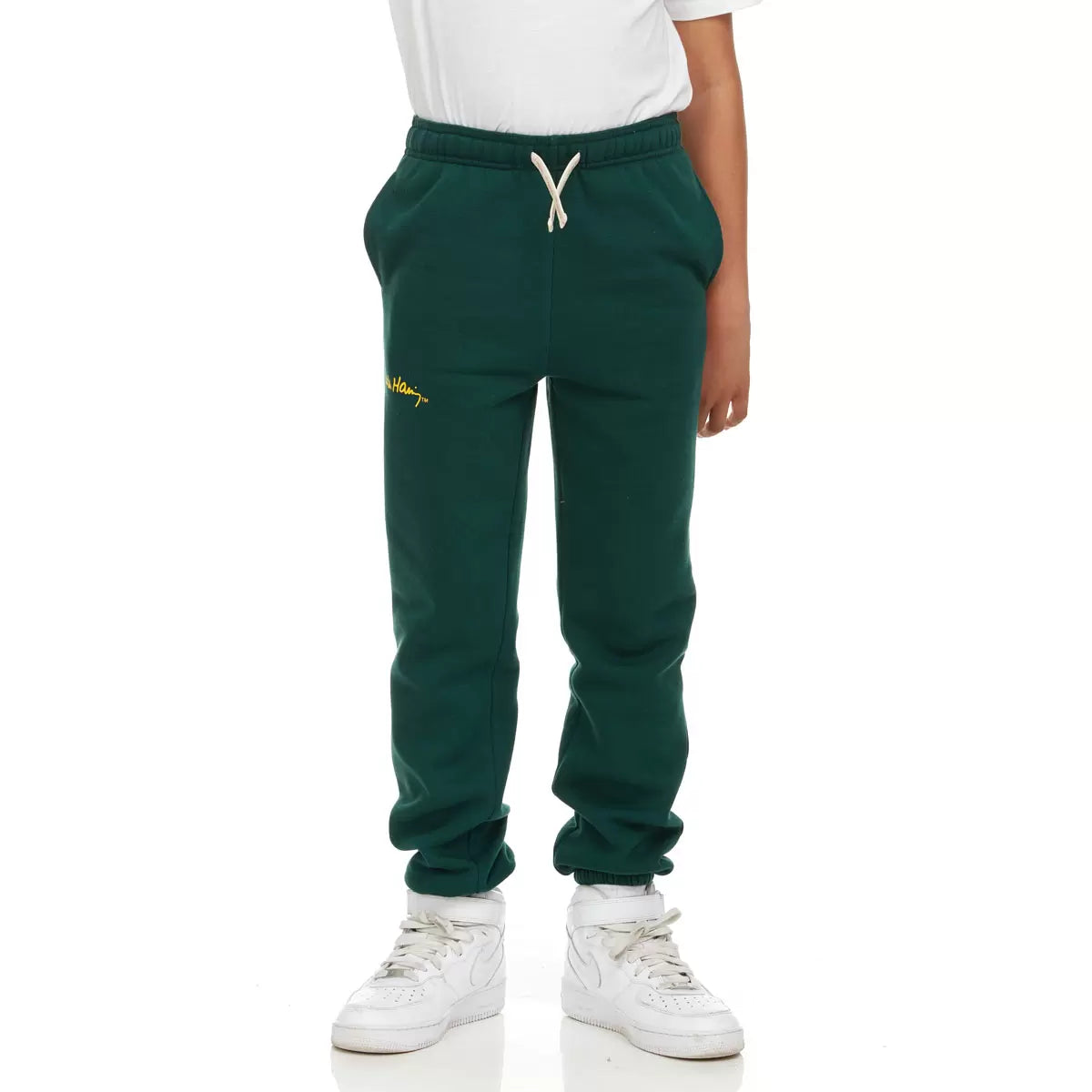 Front view of Keith Haring youth fleece joggers in green showing iconic pop art graphics, side pockets, and an elastic drawstring waistband.