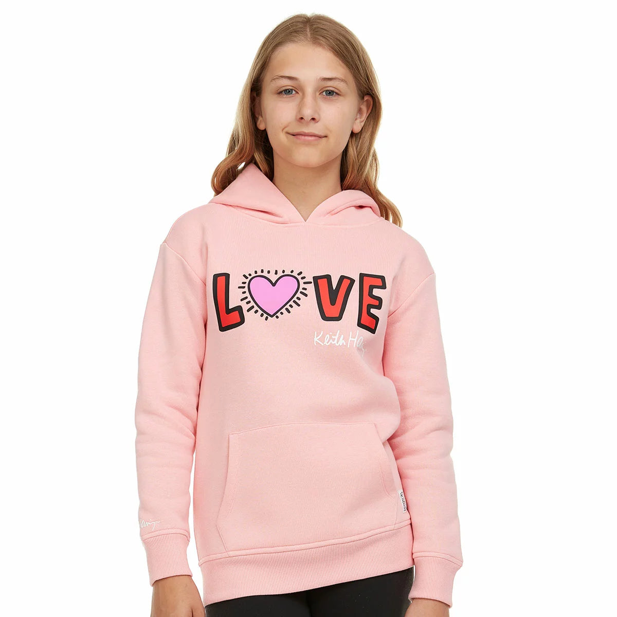 Close-up of the beige Keith Haring youth fleece hoodie showcasing the graphic front artwork, lined hood, and front kangaroo pocket on a neutral background.