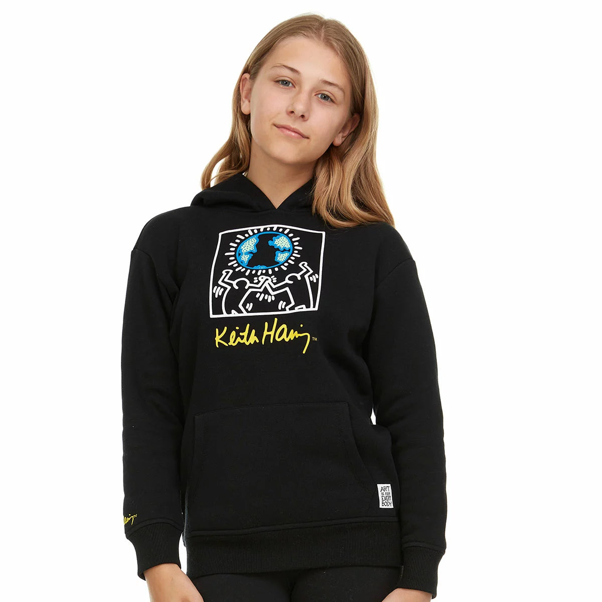 Close-up of the beige Keith Haring youth fleece hoodie showcasing the graphic front artwork, lined hood, and front kangaroo pocket on a neutral background.