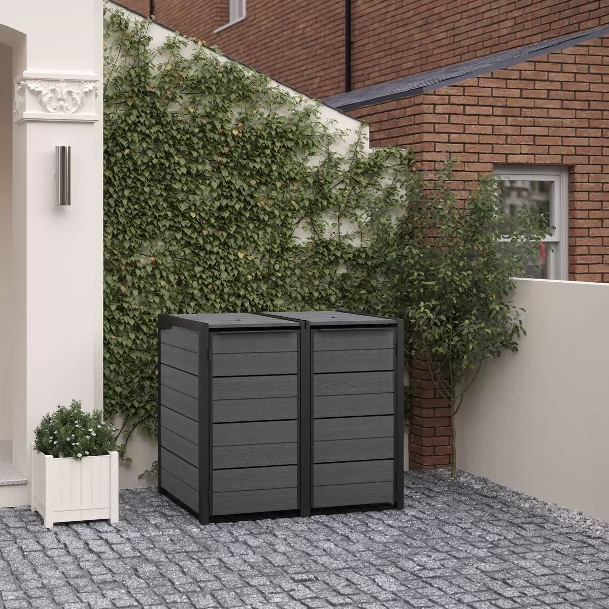 Keter Cortina Hideaway 2-section bin store in a charcoal and wood-grain finish, sitting on a modern patio with two wheelie bins inside.