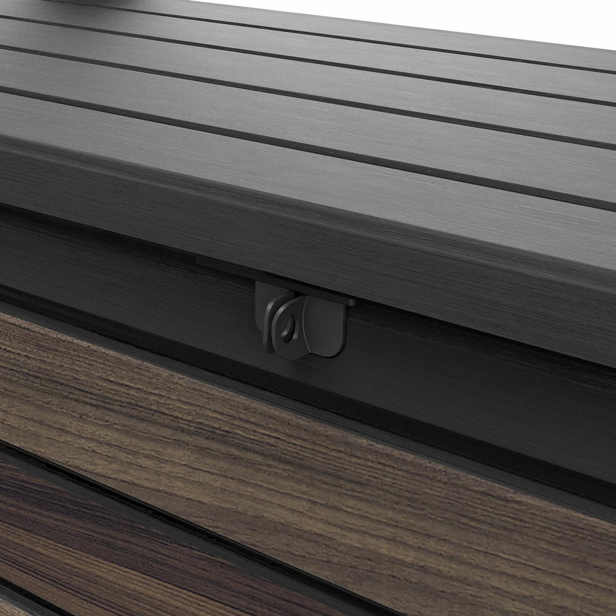 Front angle view of the brown Keter Rosewood 575L deck box featuring a realistic wood-grain texture, positioned on a modern stone patio next to outdoor green foliage.
