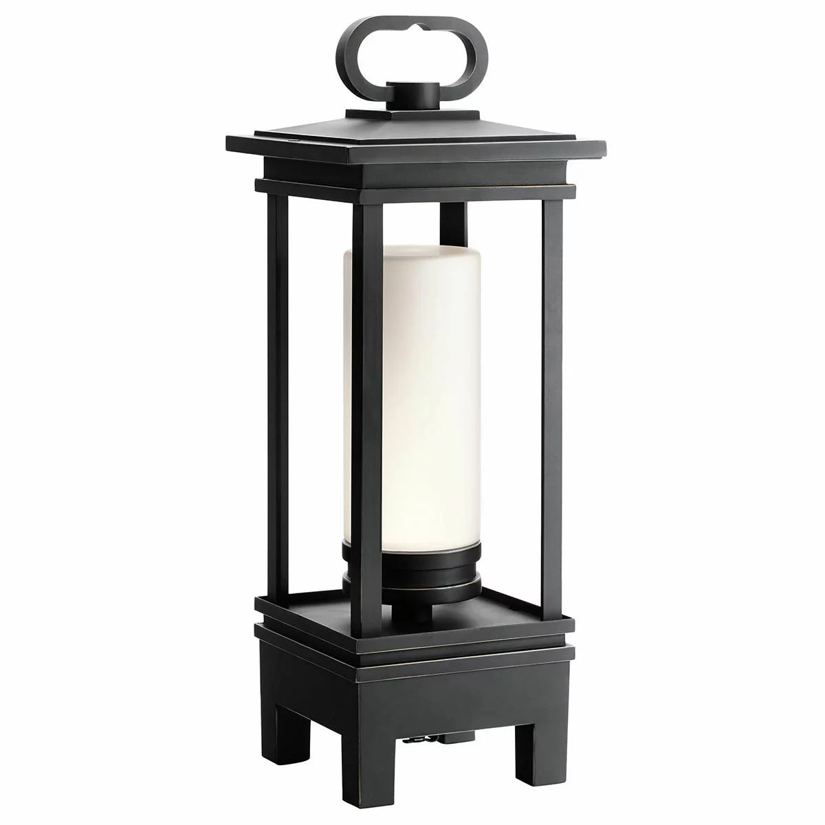 A Kichler South Hope rubbed bronze lantern with satined glass sitting on a wooden patio table, emitting a warm light.