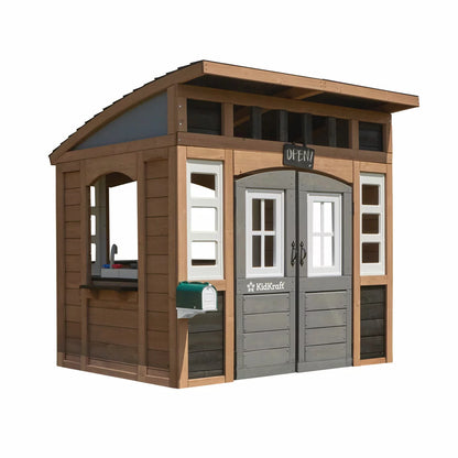 KidKraft Sunny Bluff brown wooden outdoor playhouse with curved double doors, picnic table, kitchen area, chalkboard shutters, and garden play space for children.