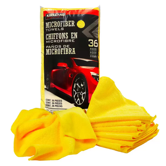 Stacked bright yellow Kirkland Signature ultra plush microfibre towels showing high-density fiber weave resting on a clean automotive workbench.
