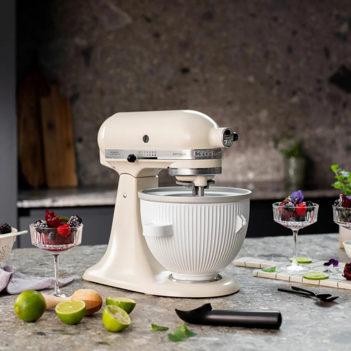 Side angle view of the white KitchenAid 5KSMICM ice cream maker bowl and churning dasher attachment mounted on a countertop stand mixer.