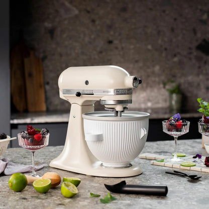 Side angle view of the white KitchenAid 5KSMICM ice cream maker bowl and churning dasher attachment mounted on a countertop stand mixer.