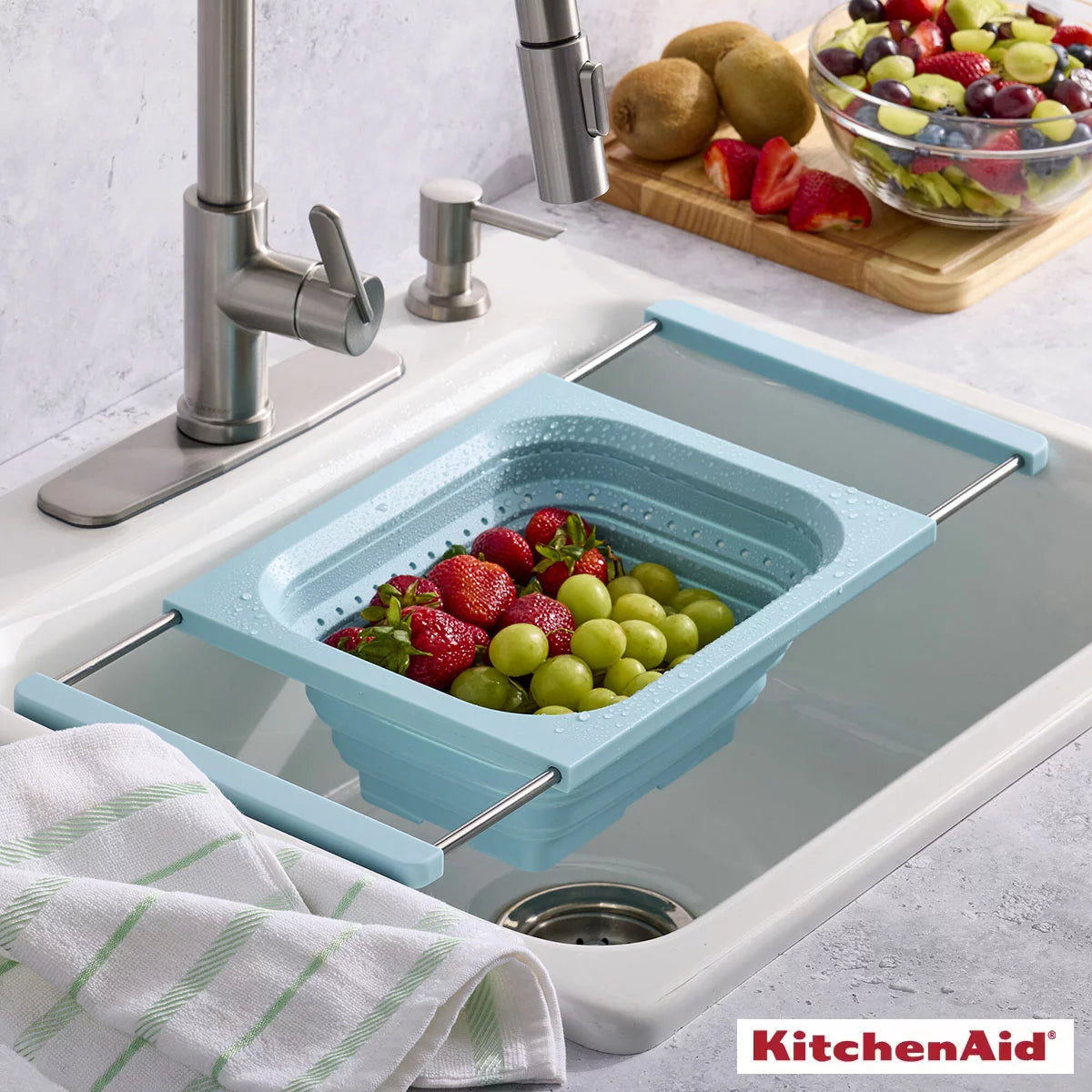 KitchenAid collapsible colander in grey and red showing space-saving flat design for kitchen storage.