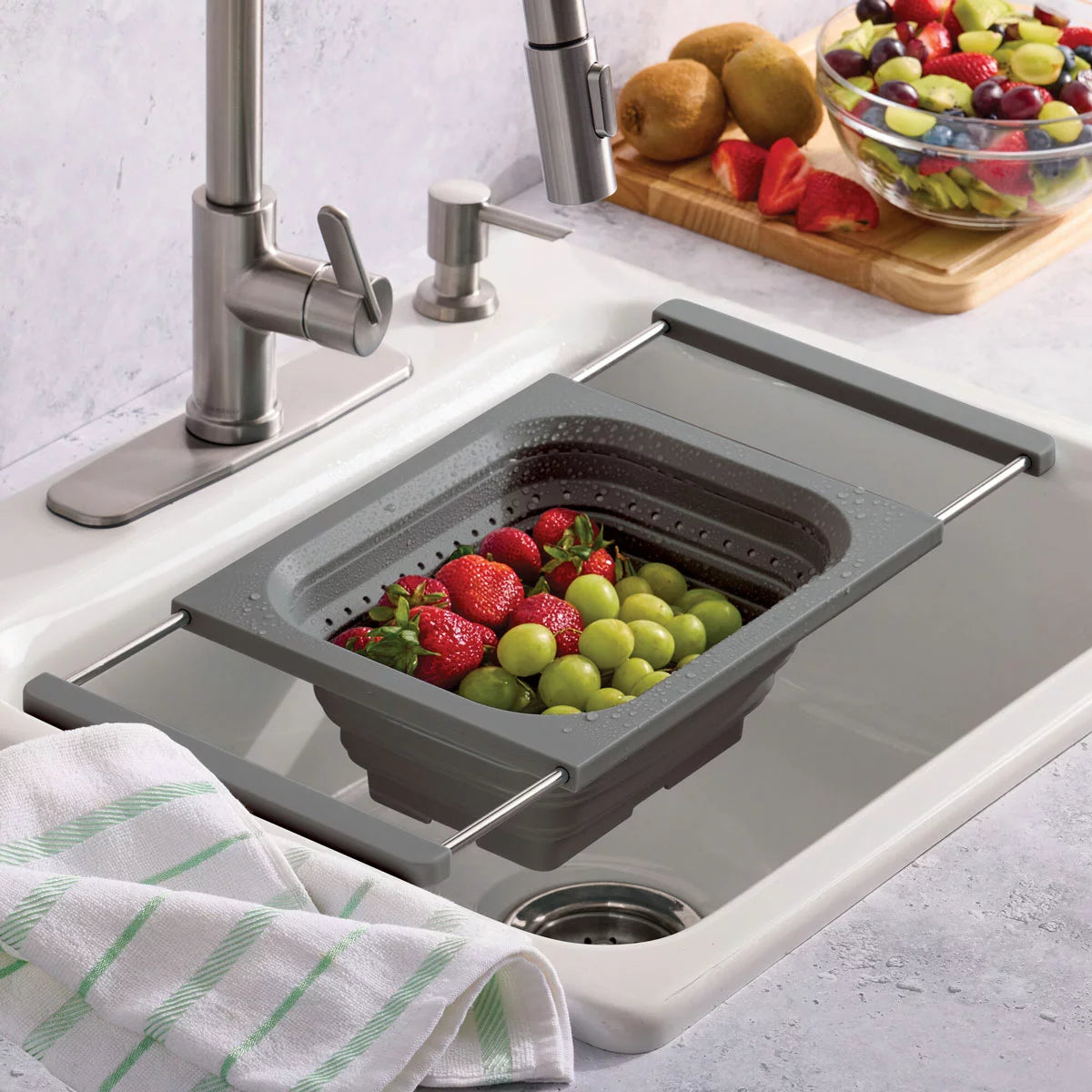 KitchenAid collapsible colander in grey and red showing space-saving flat design for kitchen storage.