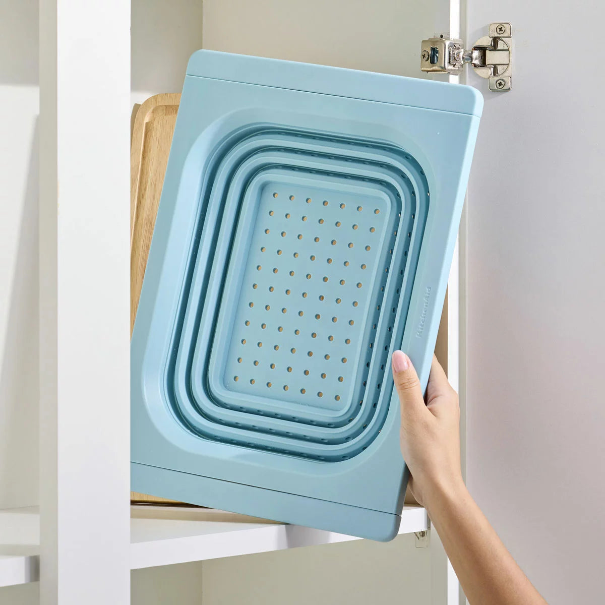 KitchenAid collapsible colander in grey and red showing space-saving flat design for kitchen storage.