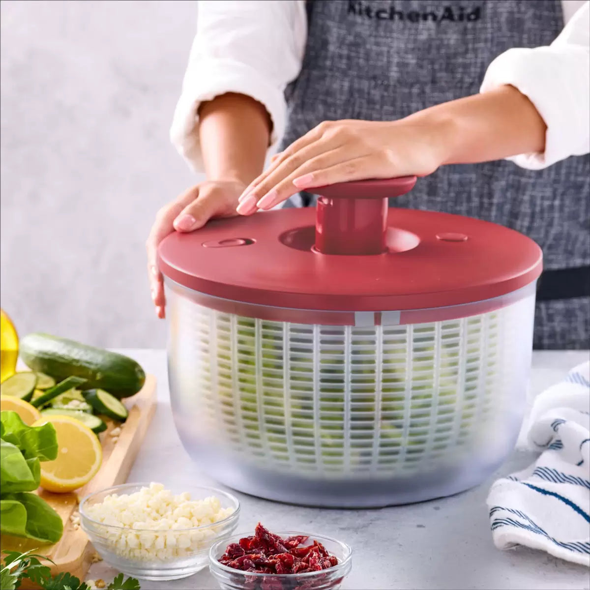 KitchenAid Salad Spinner in red and black available, demonstrating the pump-action drying mechanism on a clean kitchen countertop.
