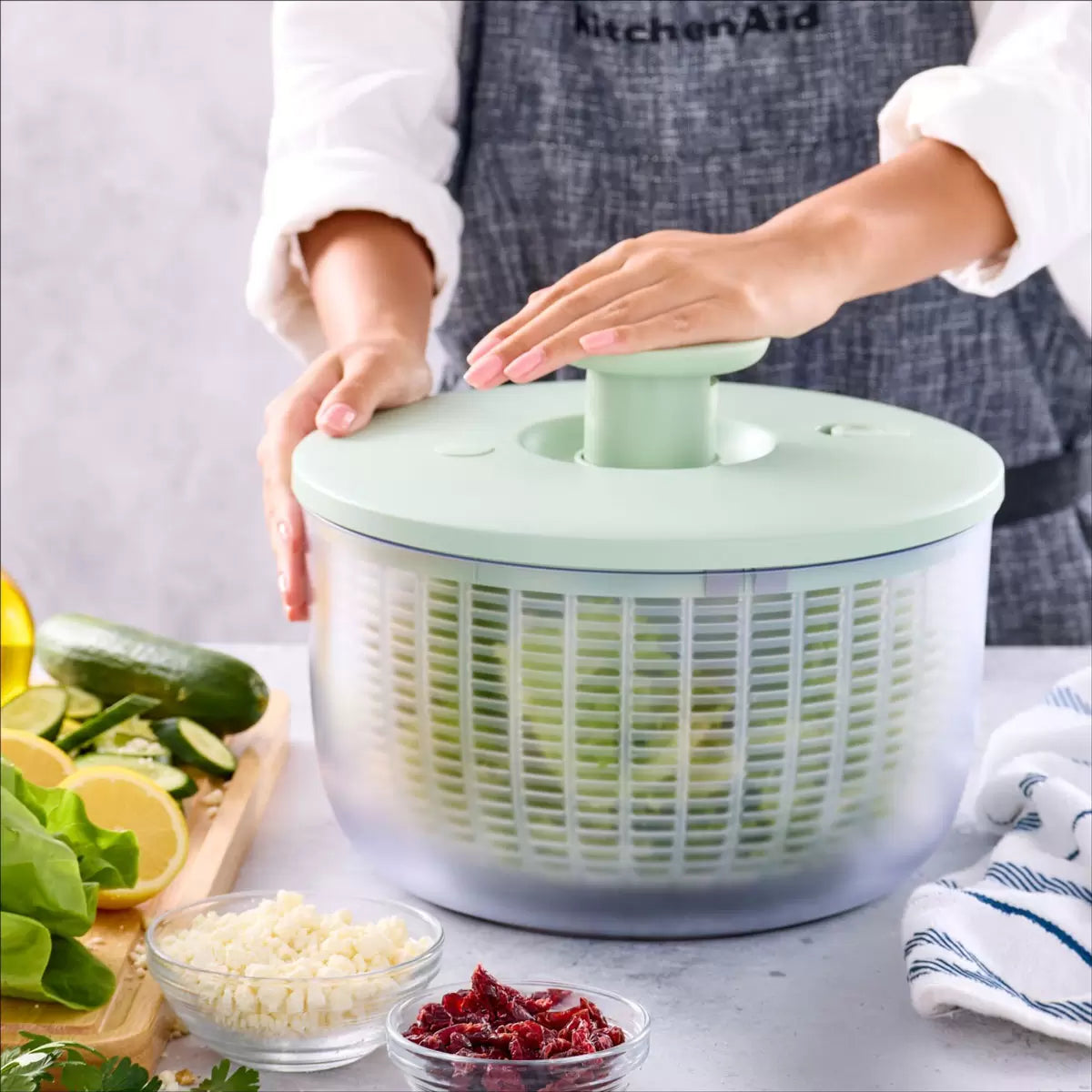 KitchenAid Salad Spinner in red and black available, demonstrating the pump-action drying mechanism on a clean kitchen countertop.