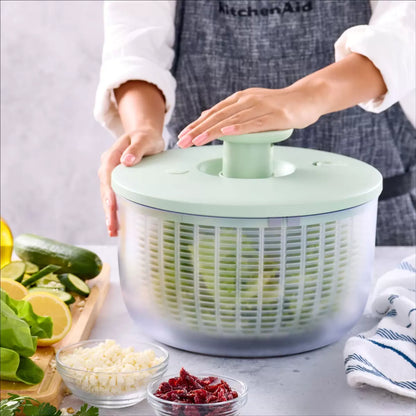 KitchenAid Salad Spinner in red and black available, demonstrating the pump-action drying mechanism on a clean kitchen countertop.