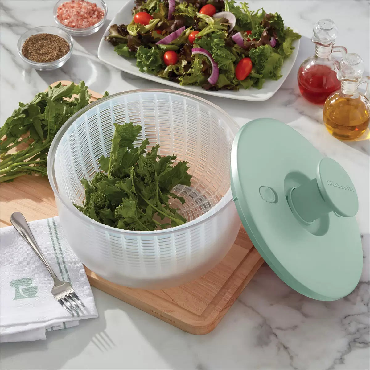 KitchenAid Salad Spinner in red and black available, demonstrating the pump-action drying mechanism on a clean kitchen countertop.