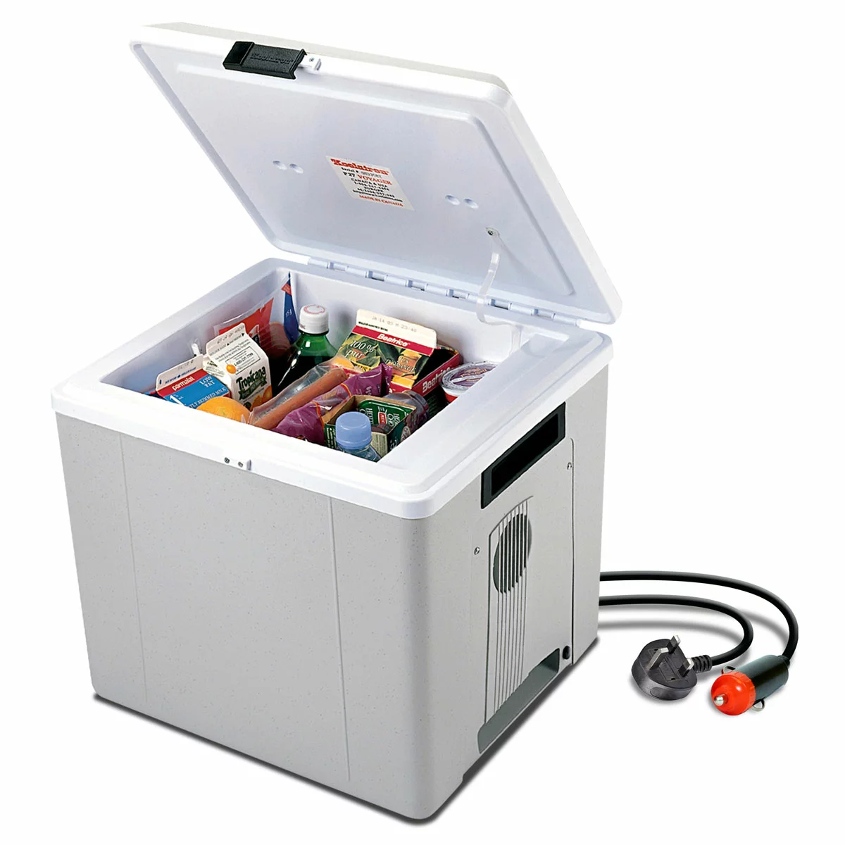 A side-angle shot of the matte grey Koolatron 27L electric cooler box standing upright as a mini-fridge on a gravel campsite, showing its durable injection-molded plastic exterior and sturdy inset handles.