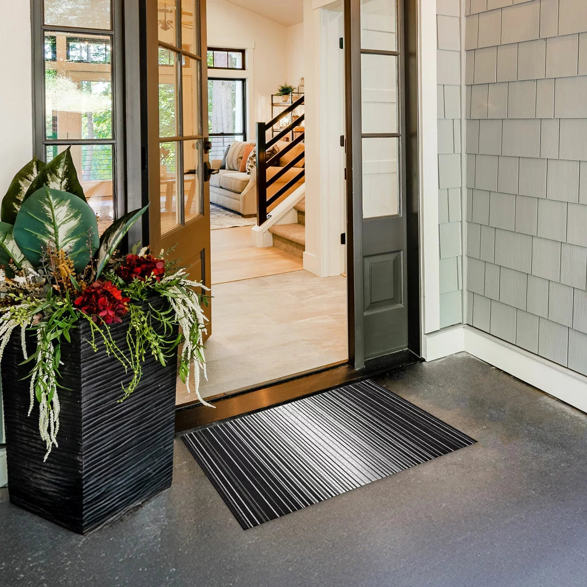 Top-down view of the black Korhani Loop Scraper Utility Mat showing its textured vinyl loop-scraper surface and low-profile edge on a modern wooden hallway floor.