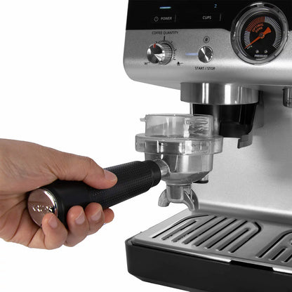 Front angle view of the black and stainless steel Krups XP801TG0 espresso machine showing the top bean hopper, portafilter attached to the group head, steam wand, and metal drip tray on a clean kitchen counter.
