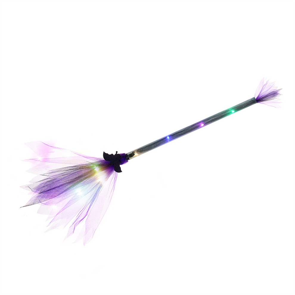 An adjustable light-up LED witch broom wrapped in gauze and ribbon glowing against a dark outdoor background.