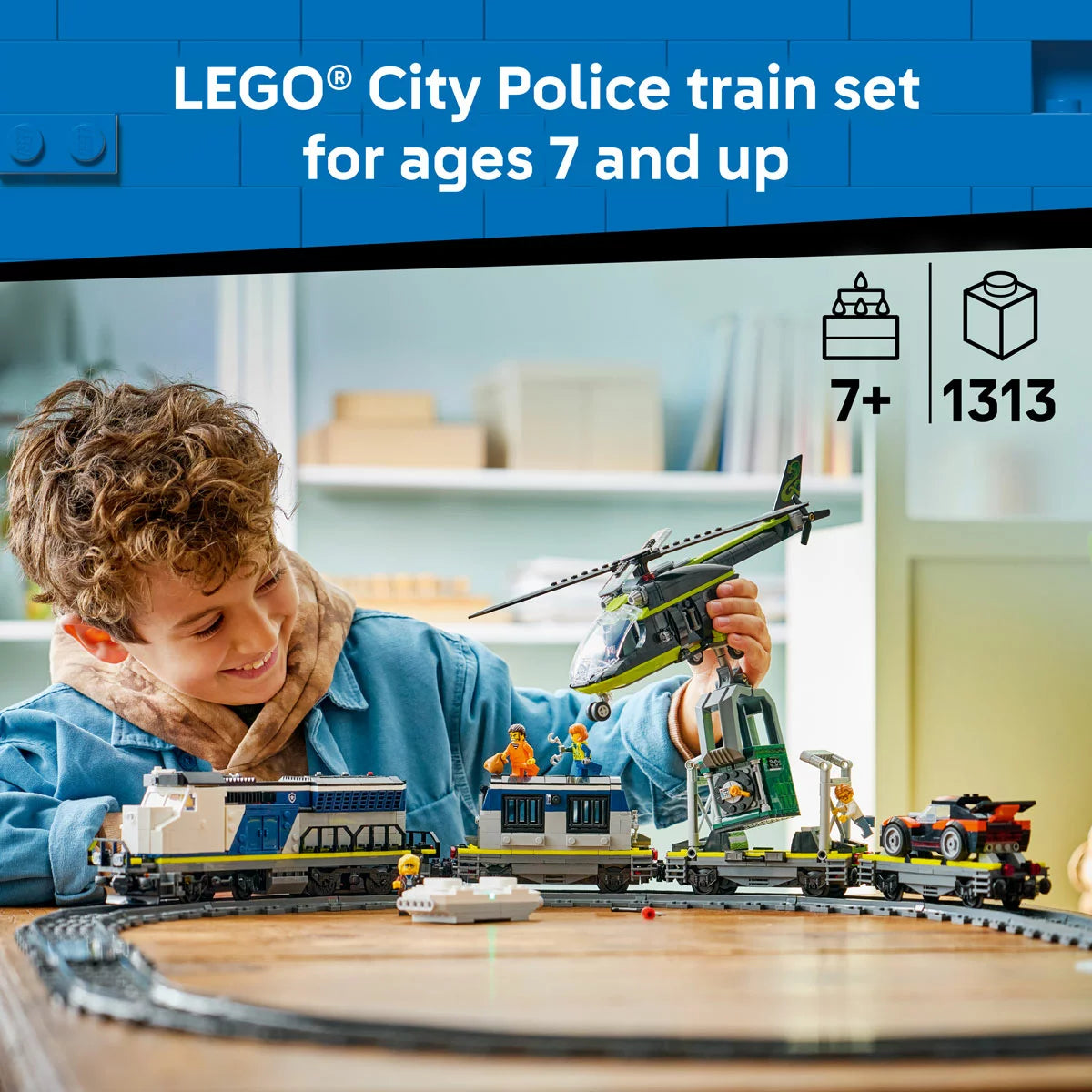 Three-quarter side view of the built blue LEGO 60508 police train traveling on tracks while a red helicopter flies overhead with a grabbing claw.