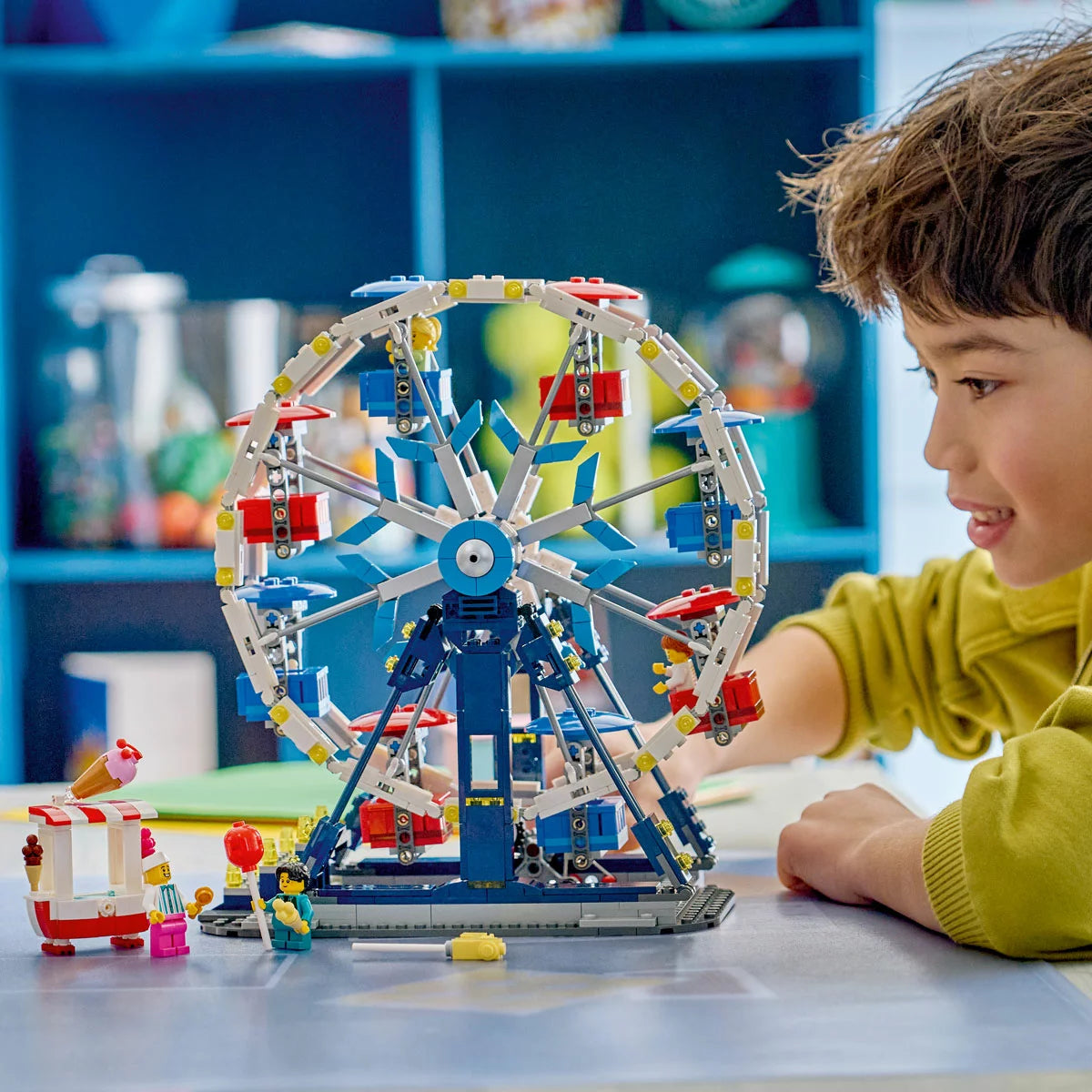 Front angle view of the colorful LEGO Creator 3-in-1 Ferris Wheel featuring eight passenger carriages, an ice cream stand, and four minifigures on a white surface.