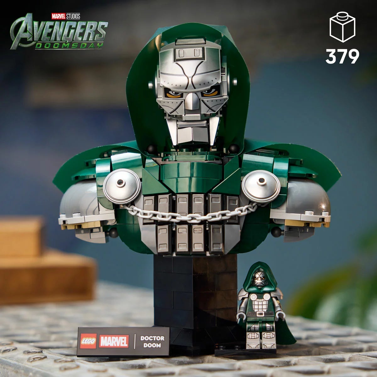Front angle view of the completed metallic gray and green LEGO Doctor Doom Bust model 76345 on a dark wooden surface.