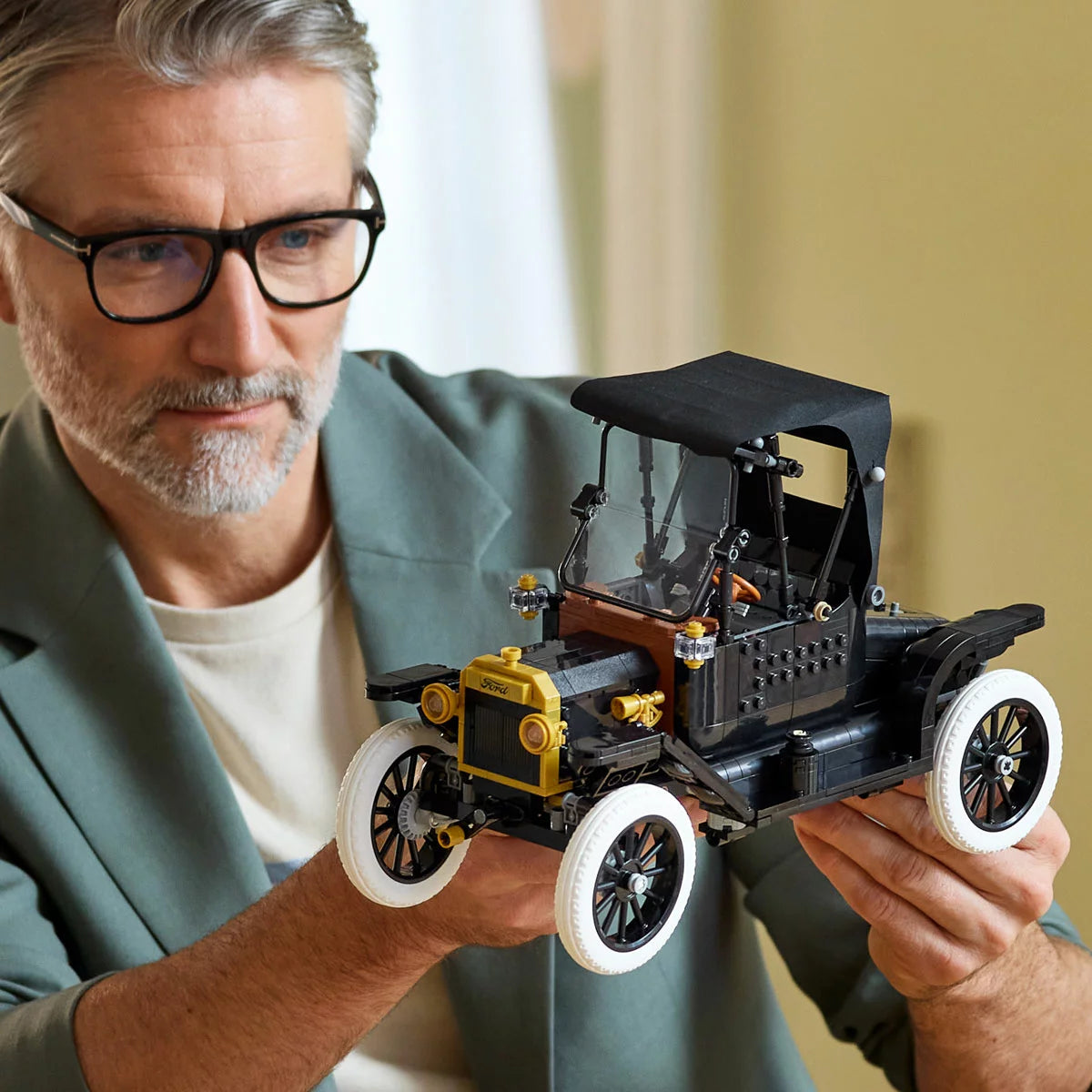 Three-quarter studio view of the built black LEGO Icons 11376 Ford Model T car display piece with gold trims, spoked wheels, white tyres, and an open driver's door.
