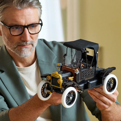 Three-quarter studio view of the built black LEGO Icons 11376 Ford Model T car display piece with gold trims, spoked wheels, white tyres, and an open driver's door.