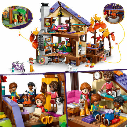 Front view of the LEGO Friends Cozy Fall Forest Cabin 42705 set showing warm autumn trees, a wooden-style house, a campfire area, and minidolls on a white display background.