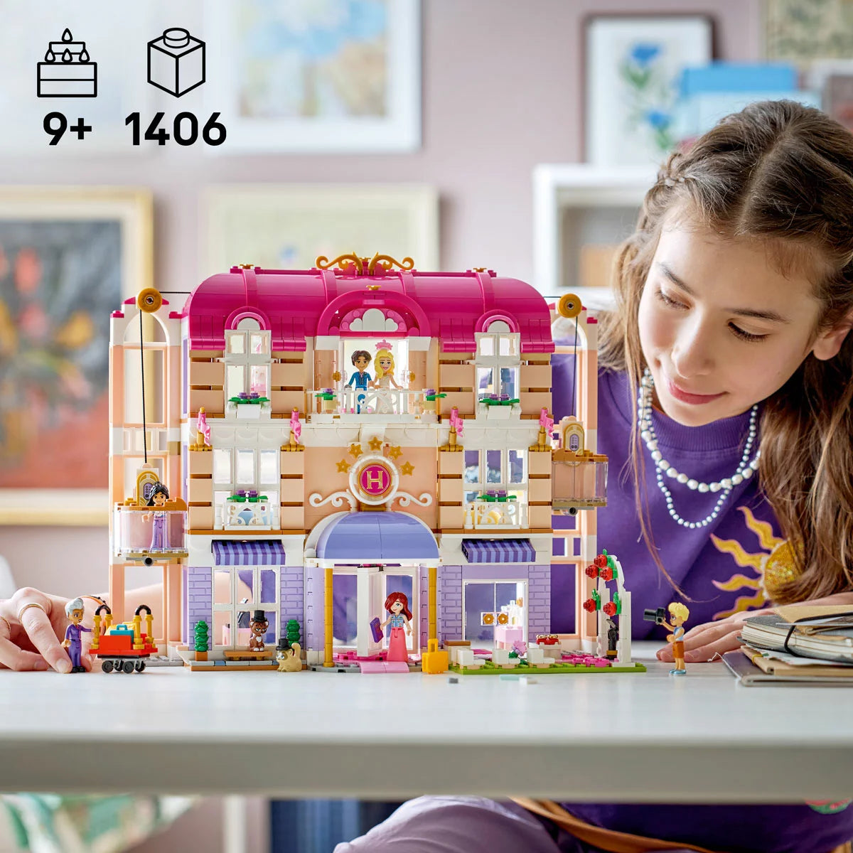 Front view of the built colorful multi-story LEGO Friends 42704 Grand Hotel featuring a purple roof, transparent balconies, and minidolls standing outside.