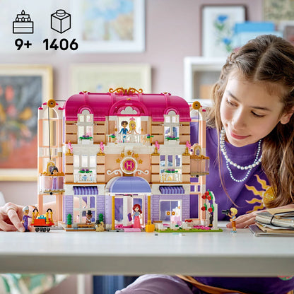 Front view of the built colorful multi-story LEGO Friends 42704 Grand Hotel featuring a purple roof, transparent balconies, and minidolls standing outside.