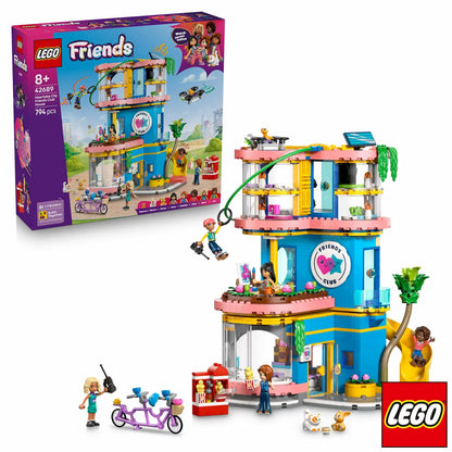 Front angle view of the colorful multi-story LEGO Friends Heartlake City Club House 42689 set featuring a red slide, zipline, climbing wall, five mini-dolls, and three pet figures on a clean white surface.