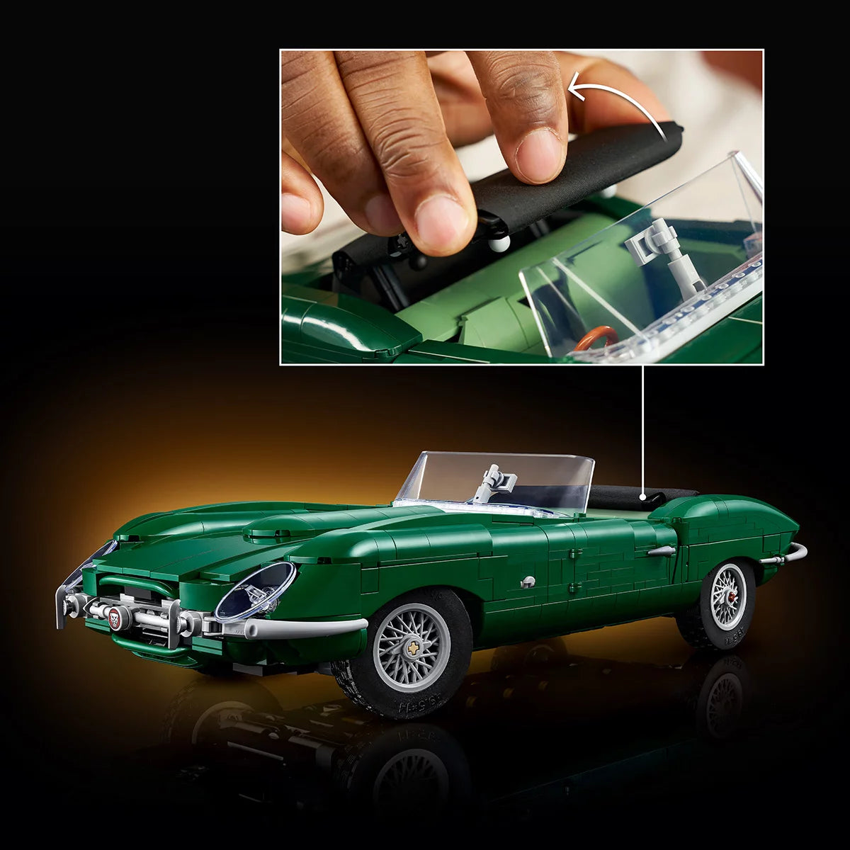 Three-quarter angle of built British green LEGO Icons Jaguar E-Type model car with wire-style wheels and dark interior on a dark wooden display surface.