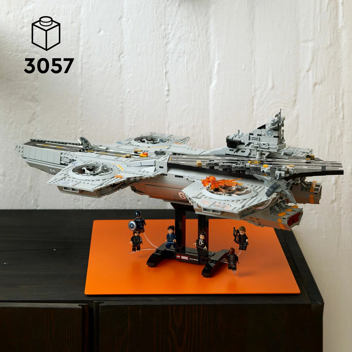 Large LEGO Marvel SHIELD Helicarrier 76354 display model with grey flight runways, dual turbine engines, micro Quinjets, and six minifigures lined up on a dark surface.