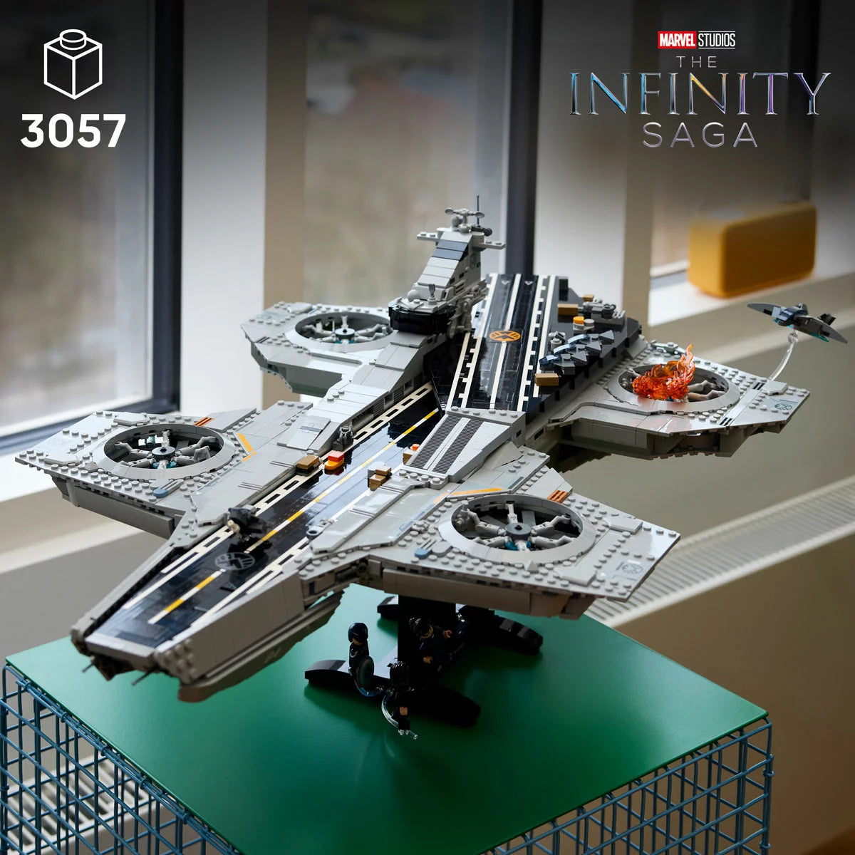 Large LEGO Marvel SHIELD Helicarrier 76354 display model with grey flight runways, dual turbine engines, micro Quinjets, and six minifigures lined up on a dark surface.