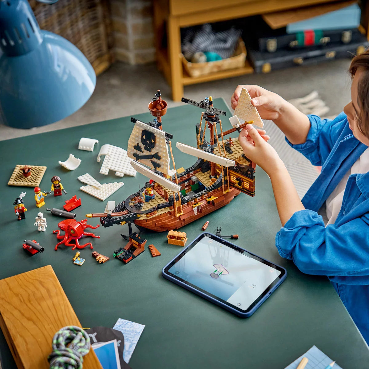 Front angle view of built LEGO Creator 31387 pirate ship model with sails raised, cannons ready, sea monster, and pirate minifigures on a plain surface.