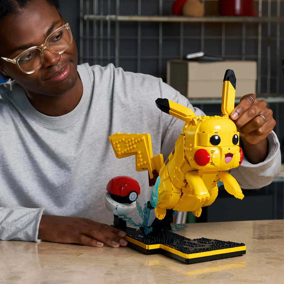 Three-quarter studio view of the built yellow LEGO 72152 Pikachu leaping from an open red and white Poké Ball on a black display base showing the number 25.