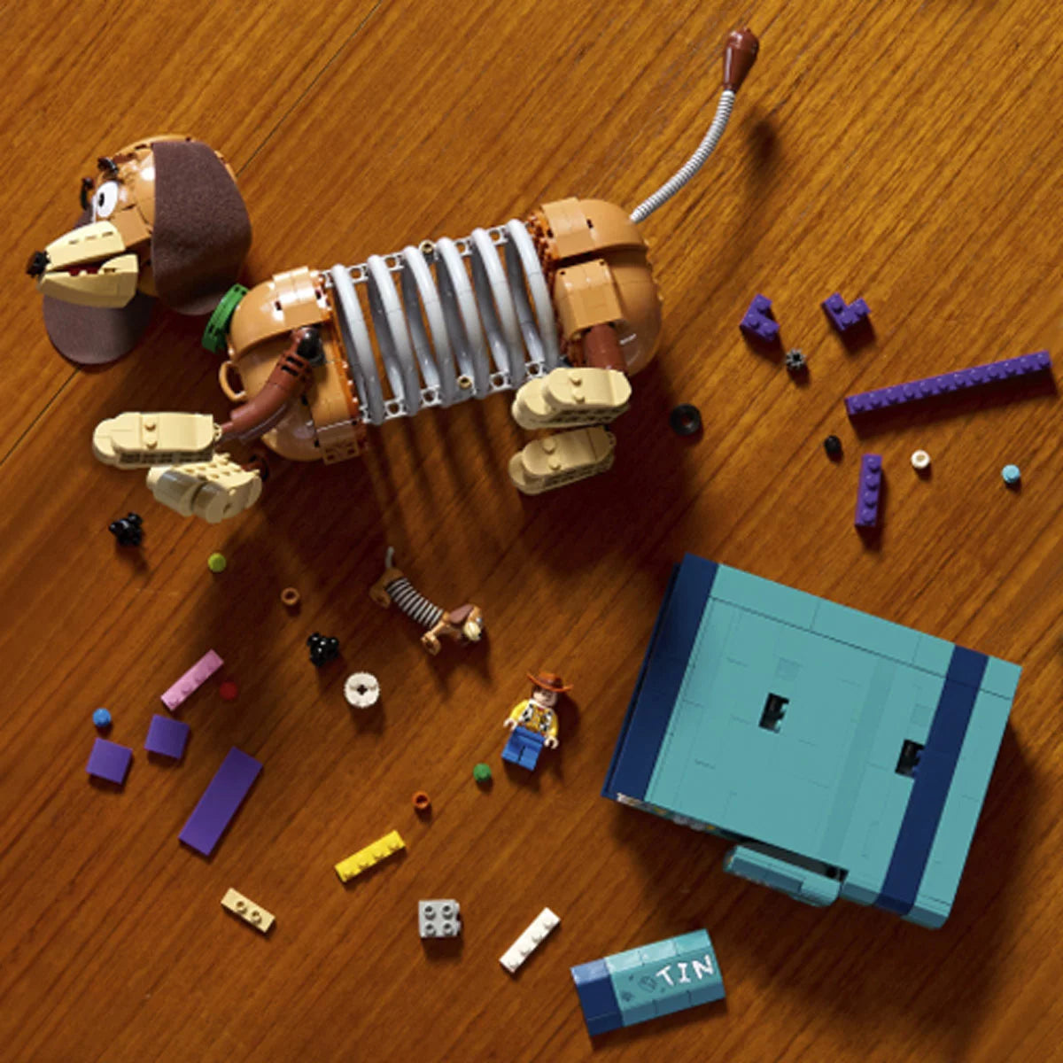 Three-quarter studio view of the built brown LEGO 43301 Slinky Dog bookends holding two blue and red brick-built books with a hidden Woody figure popping out.