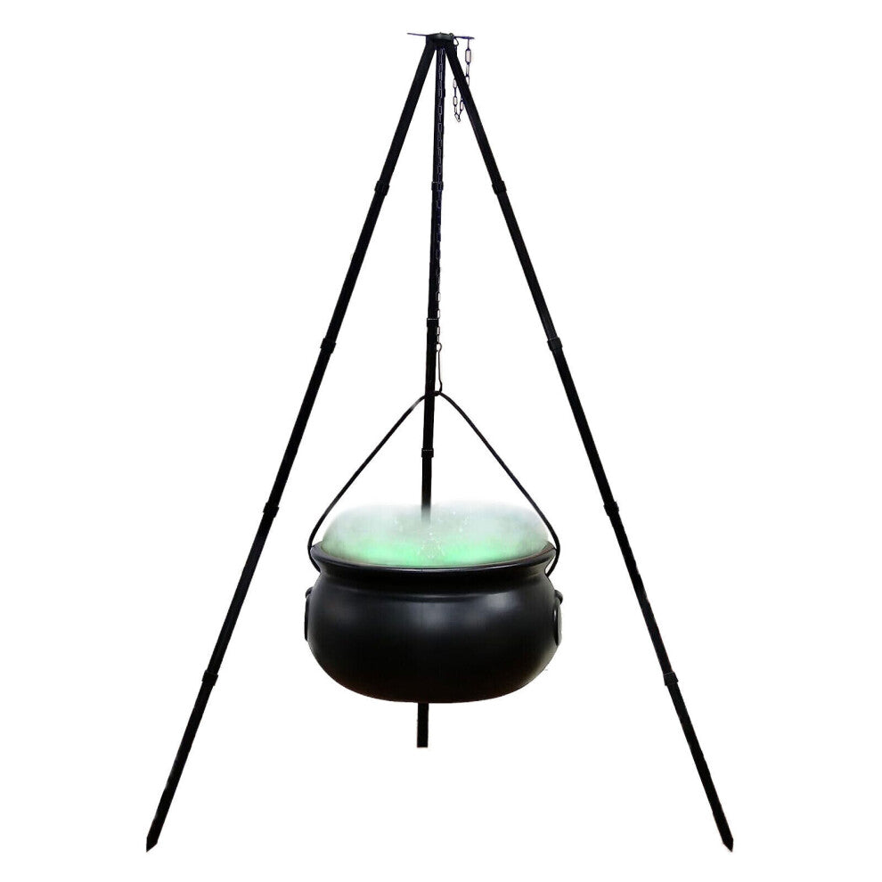 A large black witches cauldron hanging on a tripod stand in an outdoor yard setting, styled with atmospheric Halloween lighting and fog.