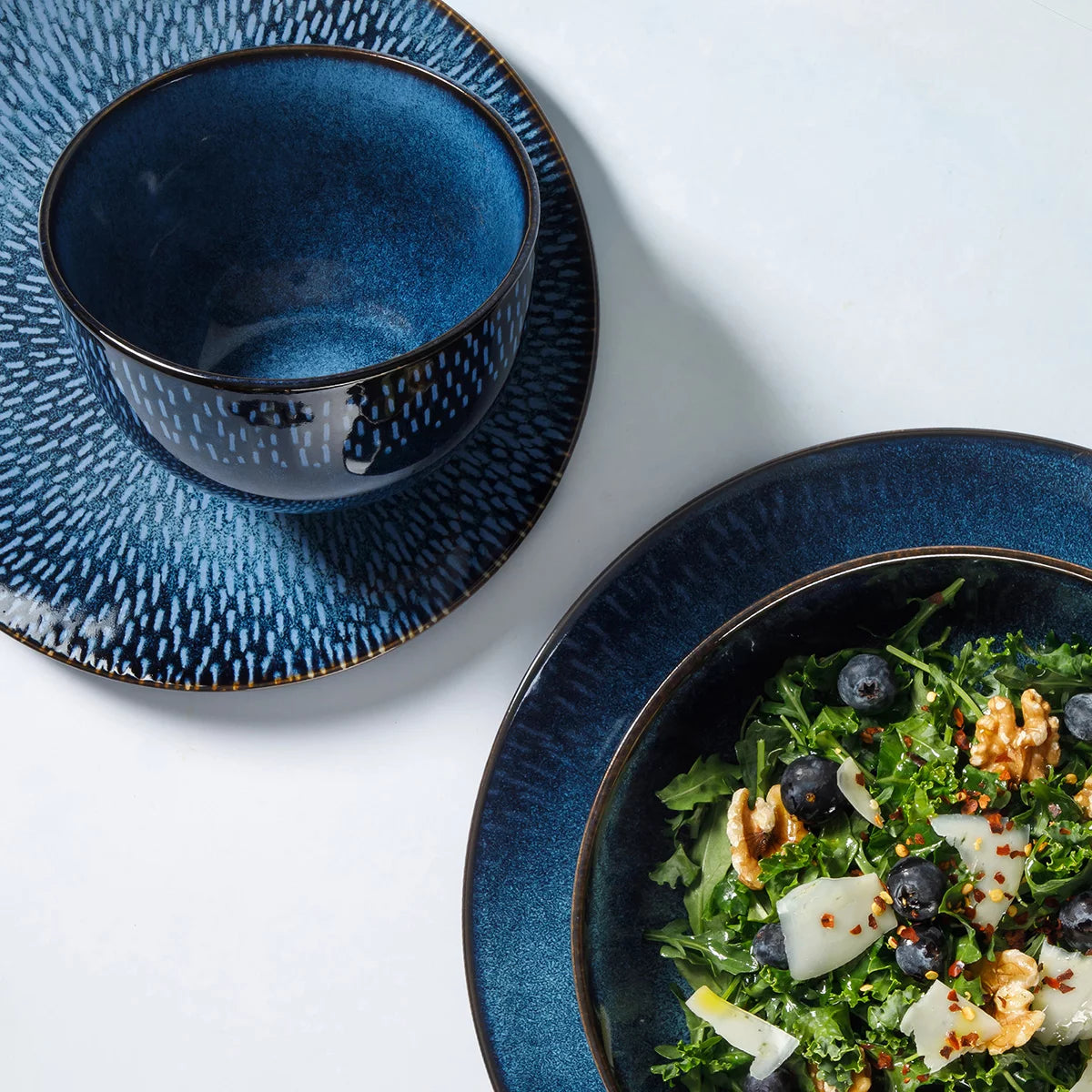 The Laurie Gates Catalina 16-Piece Reactive Stoneware Dinnerware Set arranged neatly on a table, showcasing its artisanal reactive glaze finish and complete place settings.