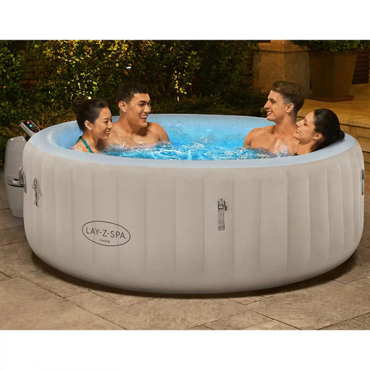 Blue illuminated water inside a Lay-Z-Spa Paris Luxe 140 AirJet inflatable hot tub set up on a dark outdoor patio decking at night.