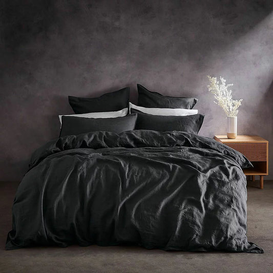 Flat lay photo of the Lazy Linen 100% washed charcoal grey linen duvet cover set neatly dressed on a king bed, showing its soft relaxed texture and matching button-closure pillowcases.