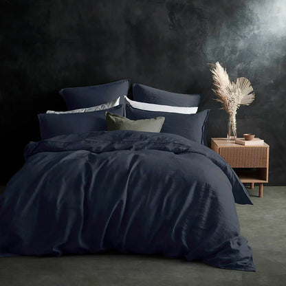 Overhead view of the Lazy Linen 100% washed navy blue linen duvet cover set draped neatly across a king-size bed, showing its soft textured finish and matching button-closure pillowcases.