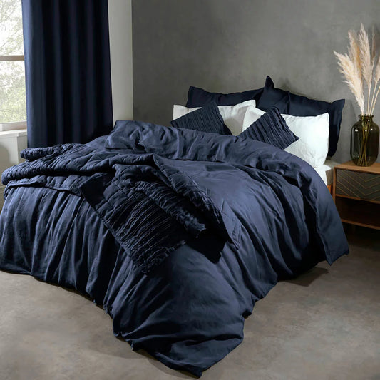 Overhead view of the Lazy Linen 100% washed navy blue linen duvet cover set draped neatly across a king-size bed, showing its soft textured finish and matching button-closure pillowcases.