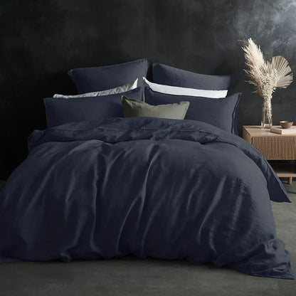 Deep navy blue Lazy Linen fitted sheet wrapped snugly around the corner of a thick mattress demonstrating its soft washed texture.