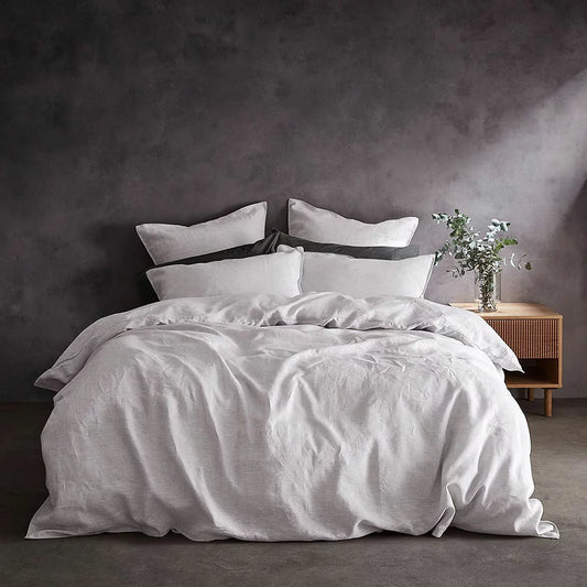 Top-down view of the Lazy Linen 100% washed white linen duvet cover set dressed on a king-size mattress with crisp, textured matching pillowcases in a sunlit bedroom.