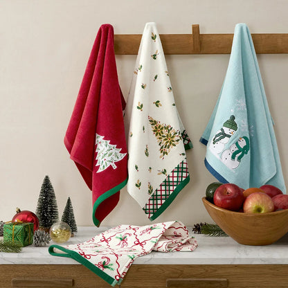 Lenox Holiday Kitchen Towels 6 Pack featuring three distinct red and green seasonal cotton patterns folded neat on a wooden countertop.