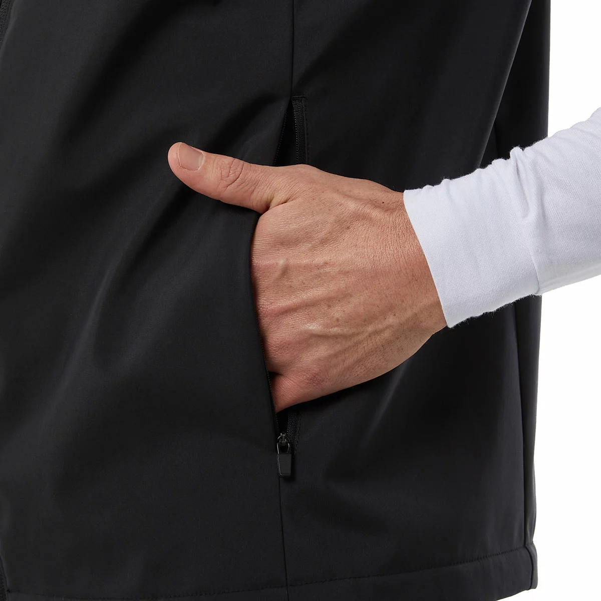 Black 32 Degrees heated vest laid flat displaying the glowing LED power button on the chest and the compact 10,000mAh battery pack resting nearby.
