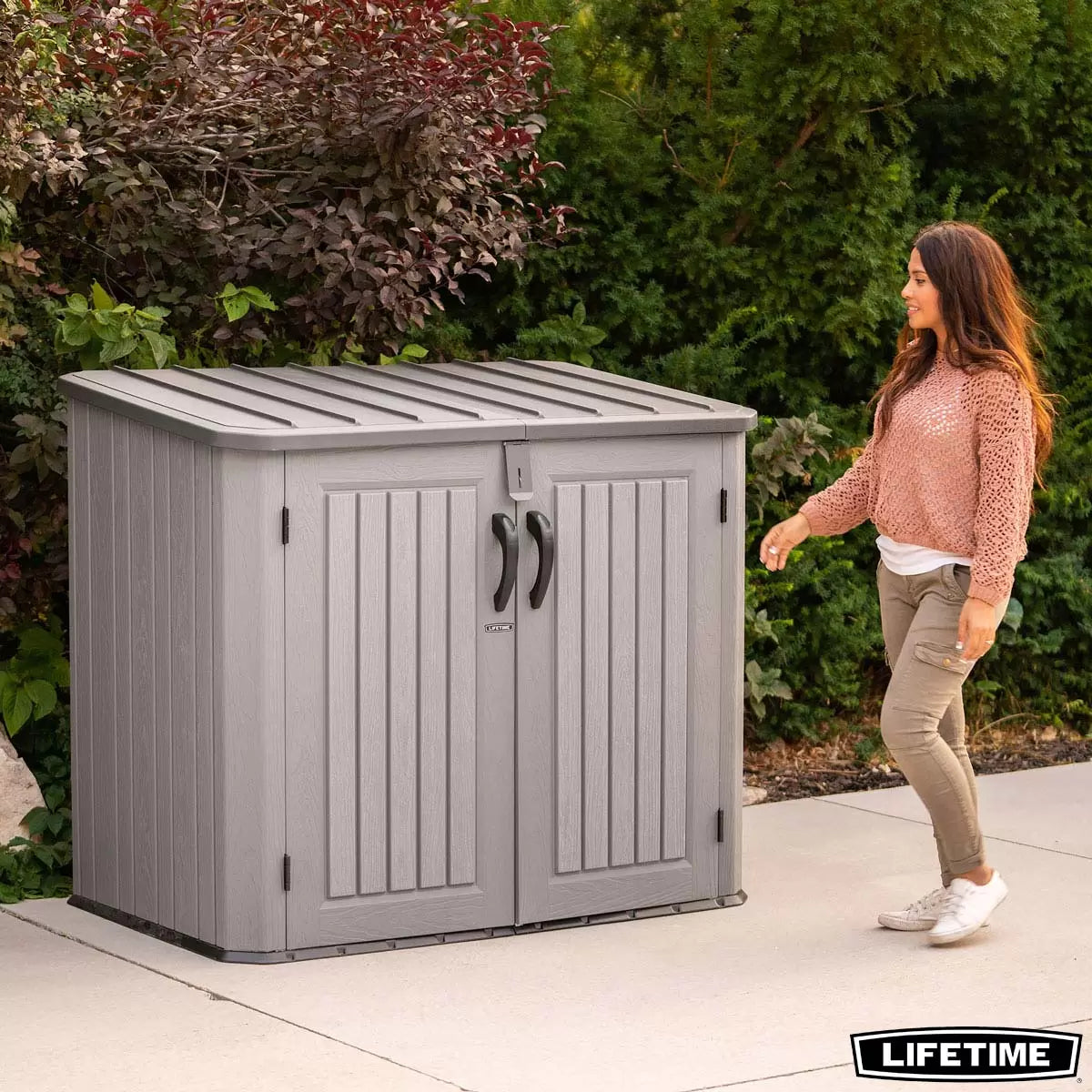 Lifetime 1300 litre horizontal garden storage shed with a realistic wood-look rough cut finish, shown with open doors revealing two standard wheelie bins.